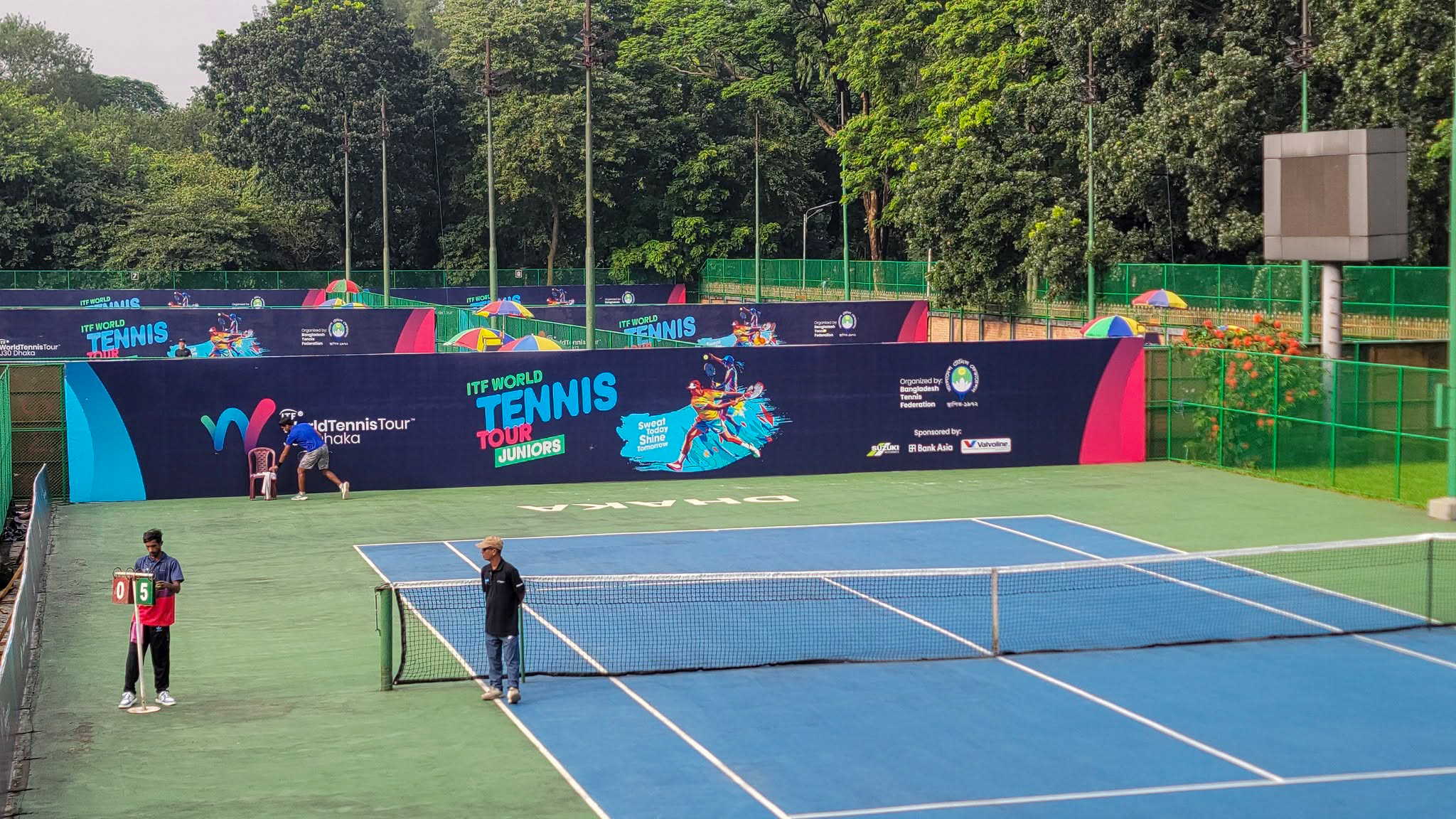Wide view of the J30 Dhaka tennis court environment with full campaign branding.